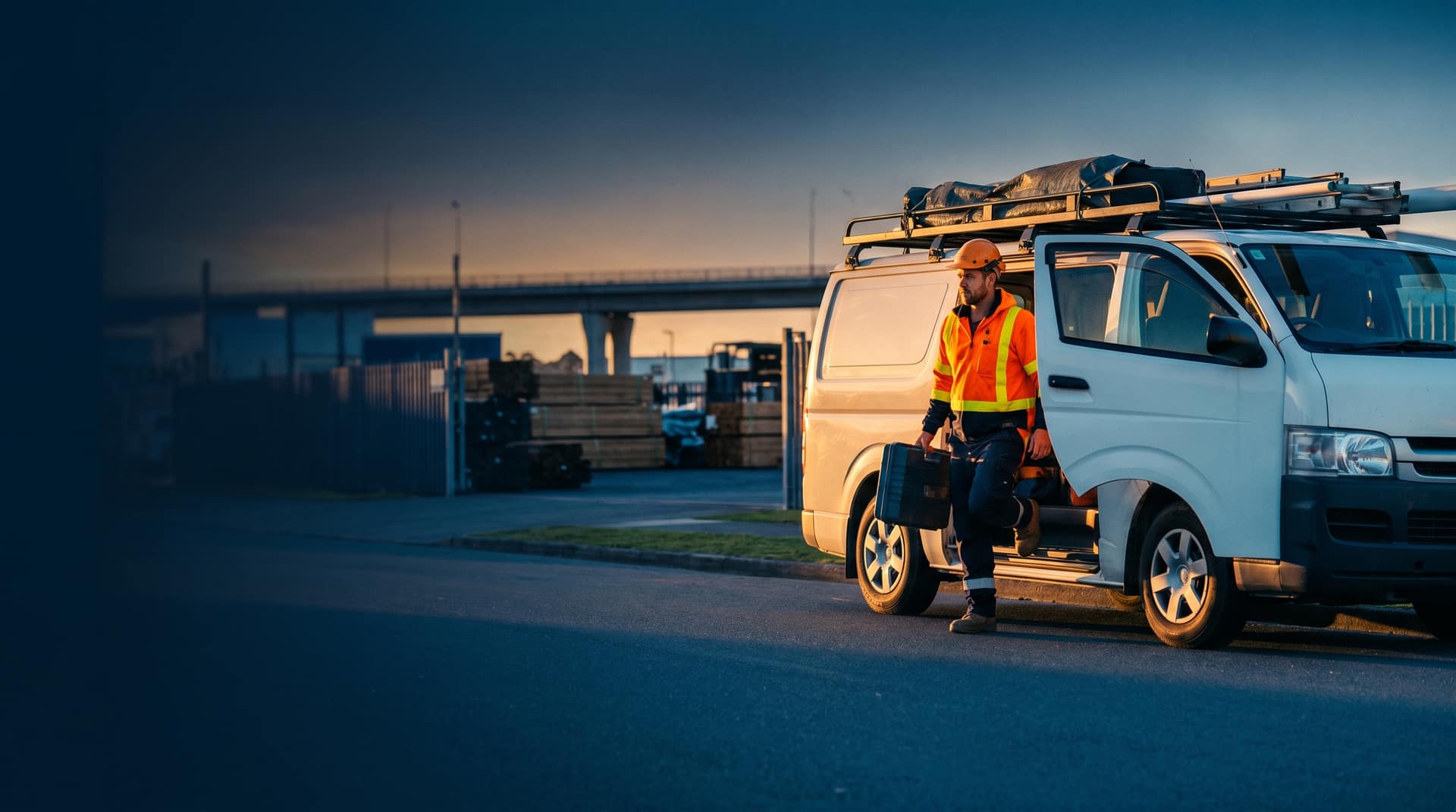 White utility vans at NZ power infrastructure site with green rolling hills and warm golden-hour light