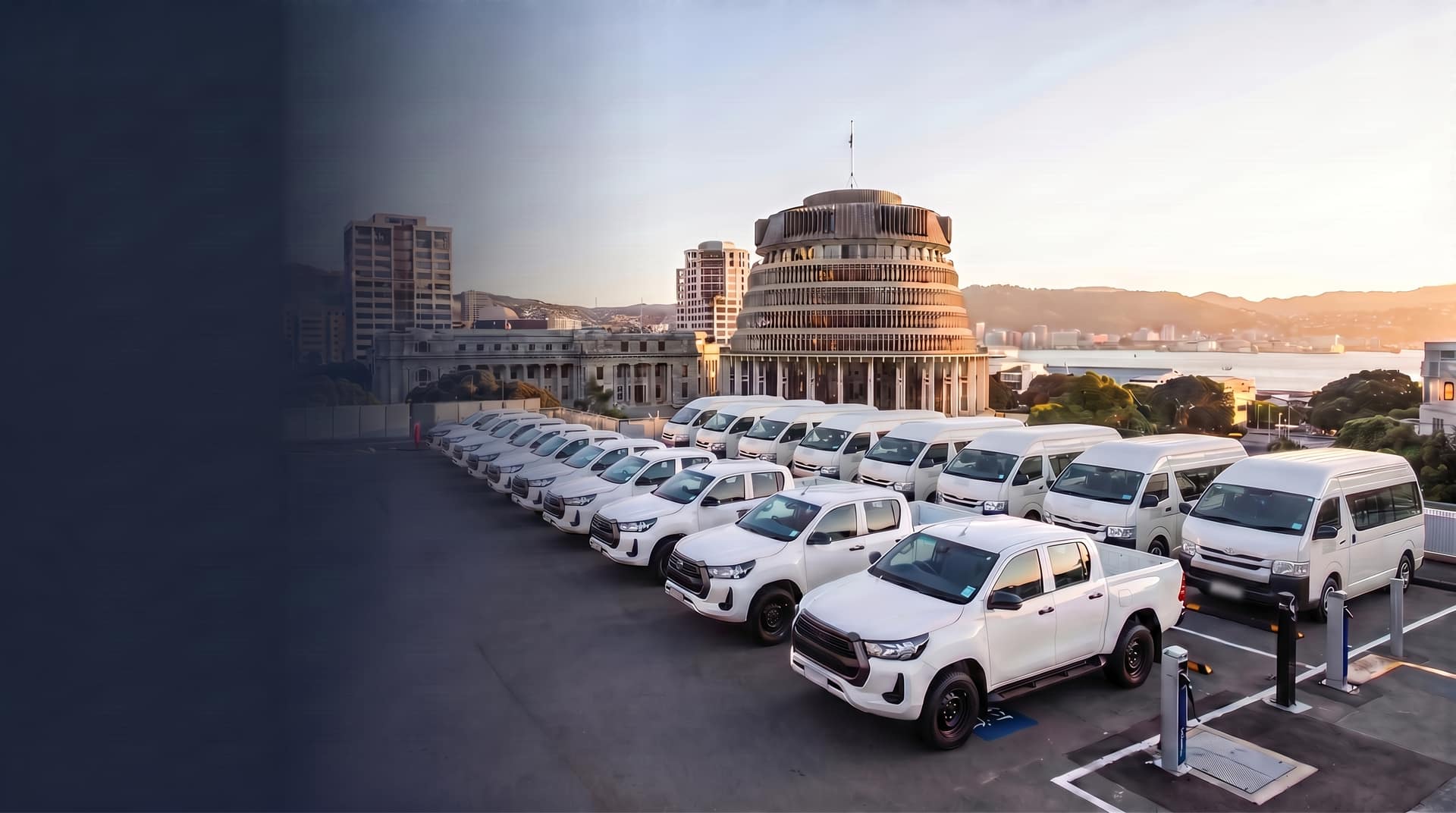 NZ government fleet vehicles including Toyota HiLux utes and HiAce vans parked at Wellington government precinct with Parliament Buildings in background