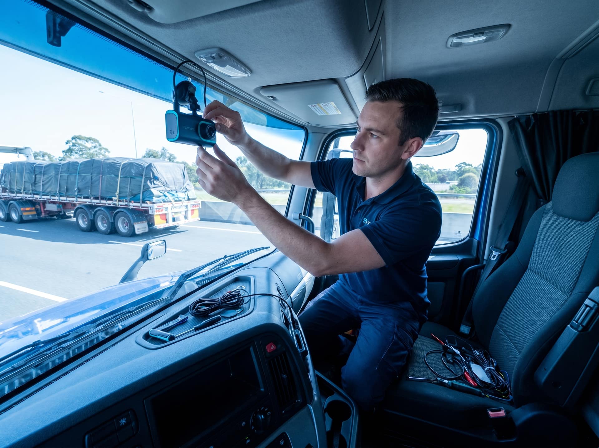 Wide shot of an AI dashcam and driver-facing camera being installed in a truck cab