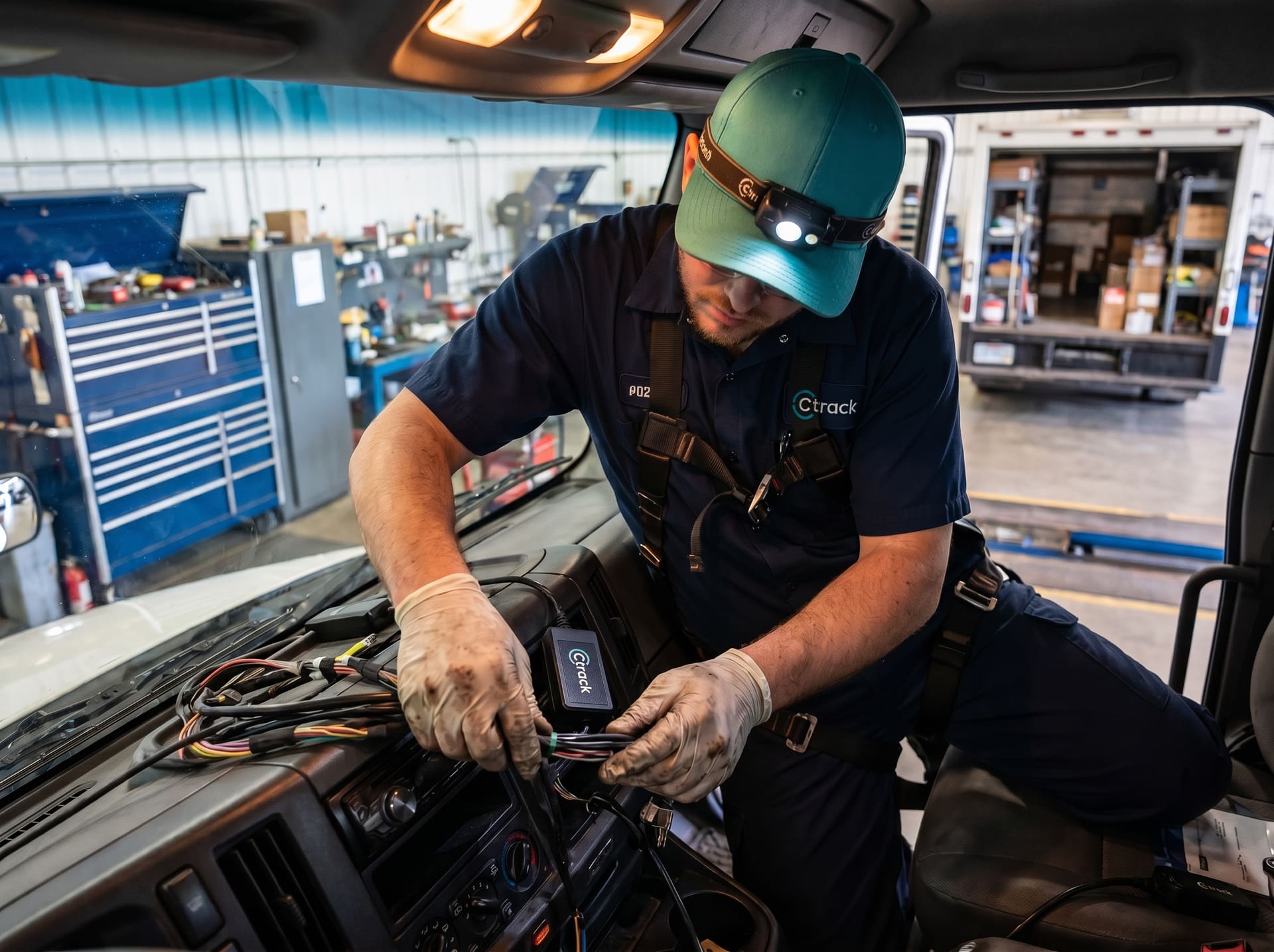 Ctrack installation technician deep under a vehicle dashboard routing a GPS tracker harness